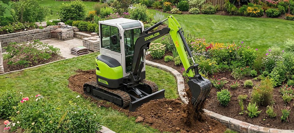 Mini pelle verte creusant le sol dans un jardin, entourée de fleurs et de plantes.