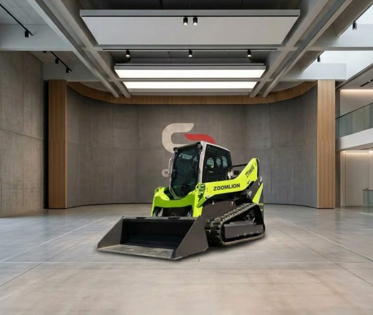 Chargeuse compacte verte et noir sur une surface en béton, avec un ciel clair en arrière-plan.