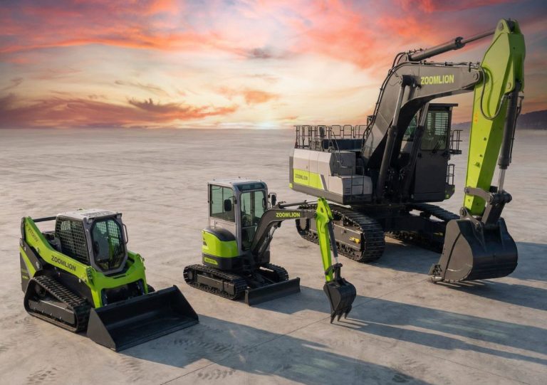 Trois engins de chantier et en arrière-plan, un paysage désertique au coucher du soleil.